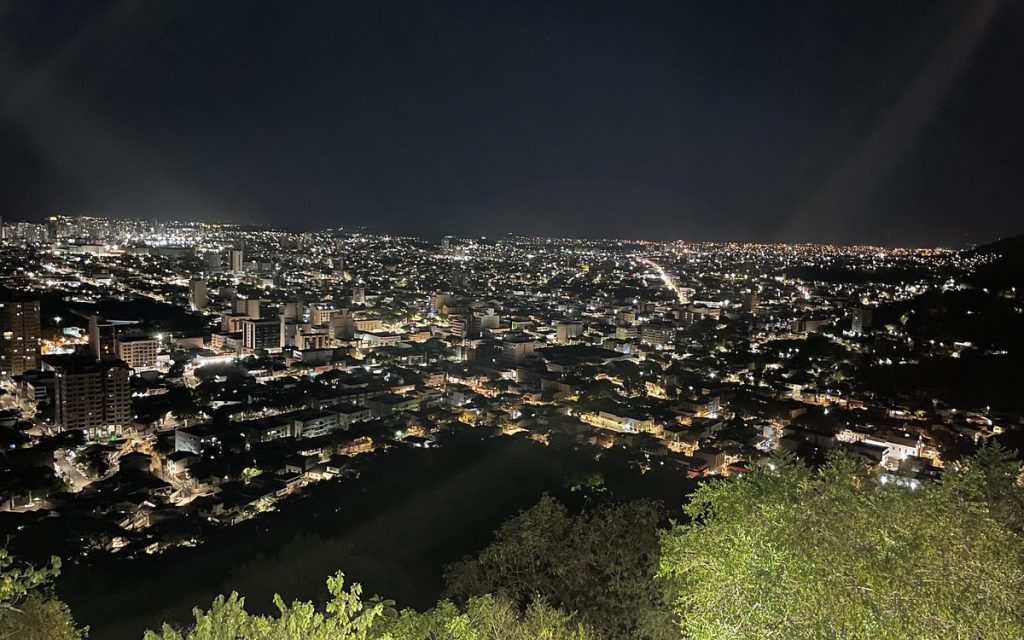 City lights spreading across a valley at night, seen from a hilltop