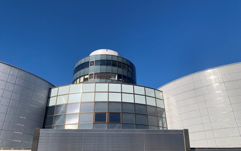 Modern cylindrical glass building against a clear blue sky
