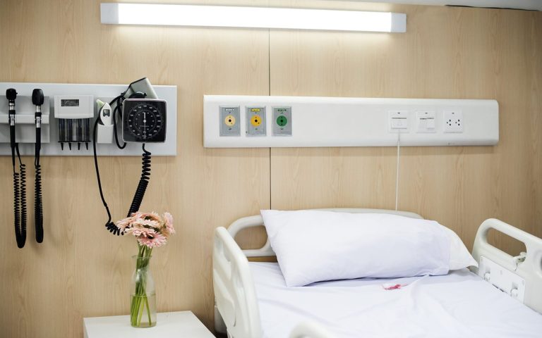 Clean hospital room with a made bed and wall-mounted diagnostic equipment