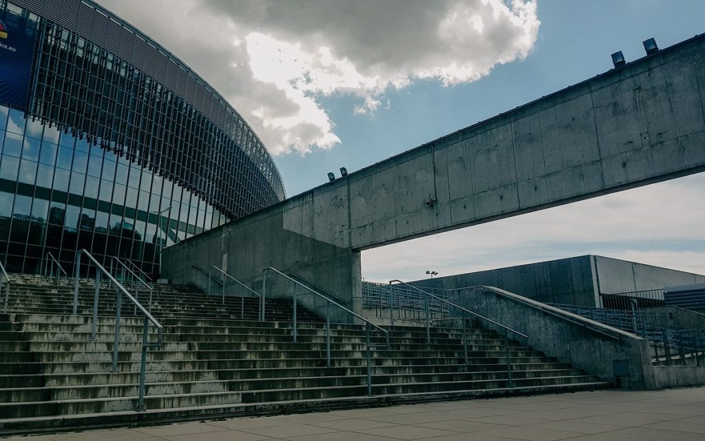 Glass-fronted building connected to a neighbouring structure by an elevated concrete walkway