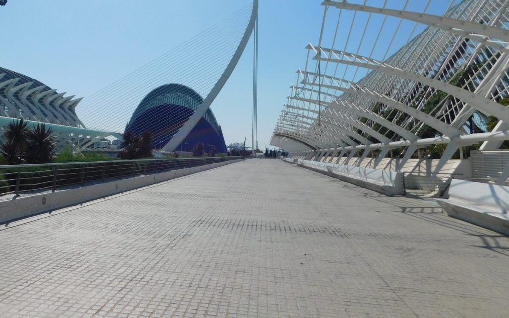 Wide elevated walkway beside white modern architecture under a blue sky