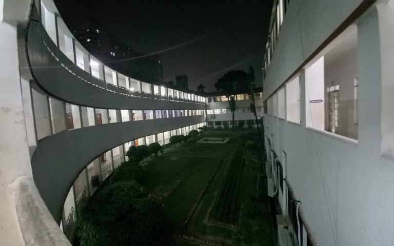 Curved building wings wrapping around a central courtyard garden at dusk