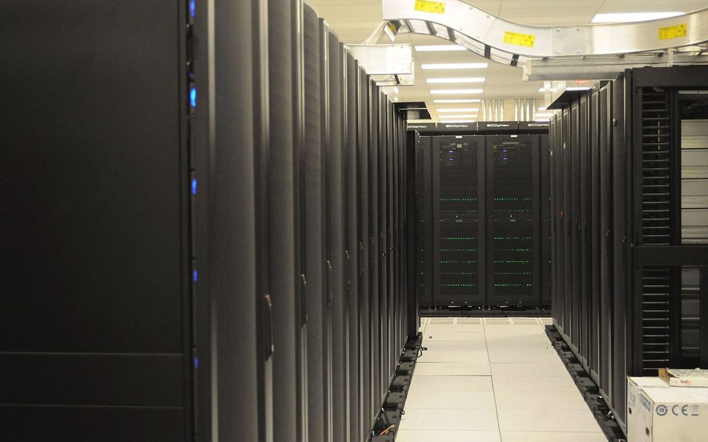 Long aisle between rows of black server racks in a brightly lit data center