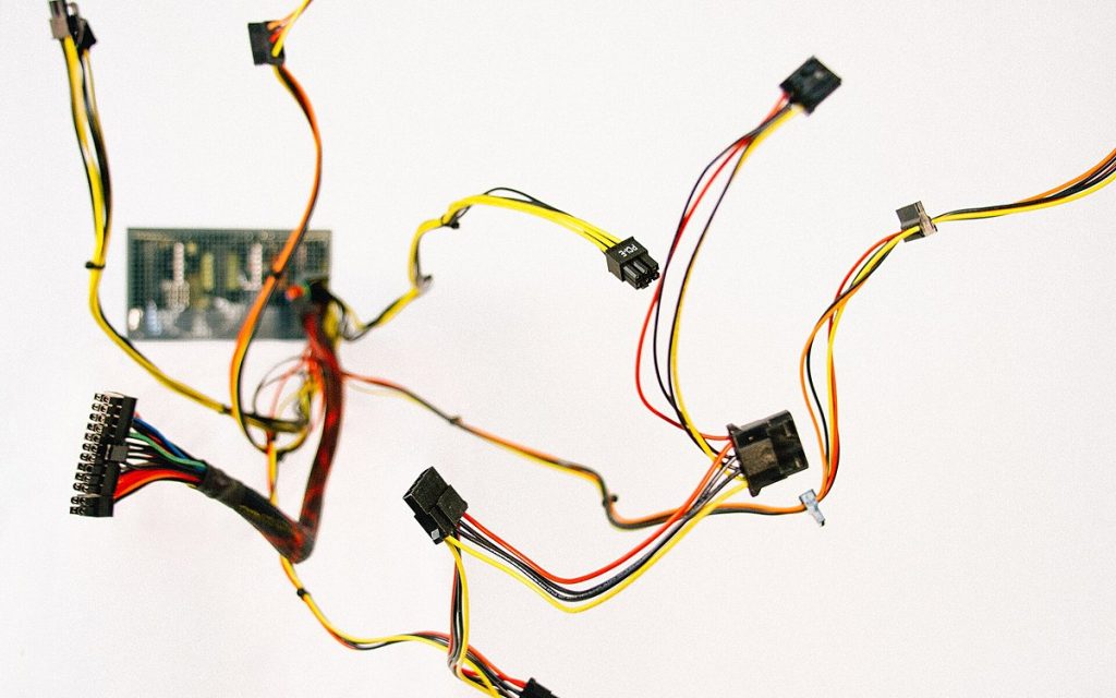 Loose, unconnected computer wires and connectors scattered across a white surface